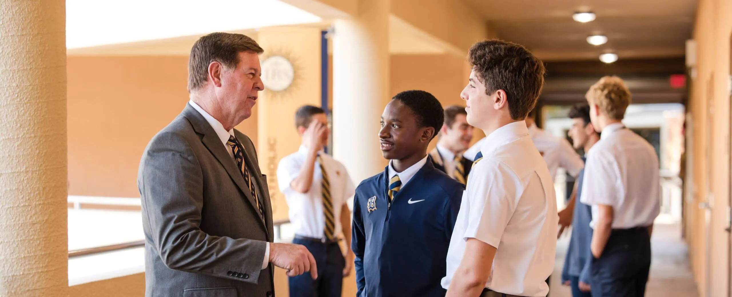 Belen Jesuit Principal Jose E. Roca ('84) speaking to students in a school hallway.