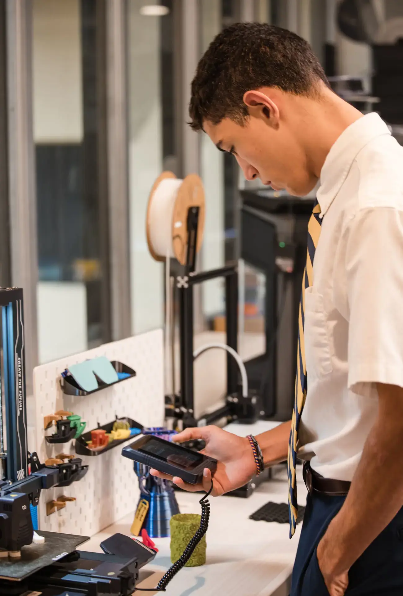 Belen Jesuit student Robotics Team member using a machine in a STEAM class.