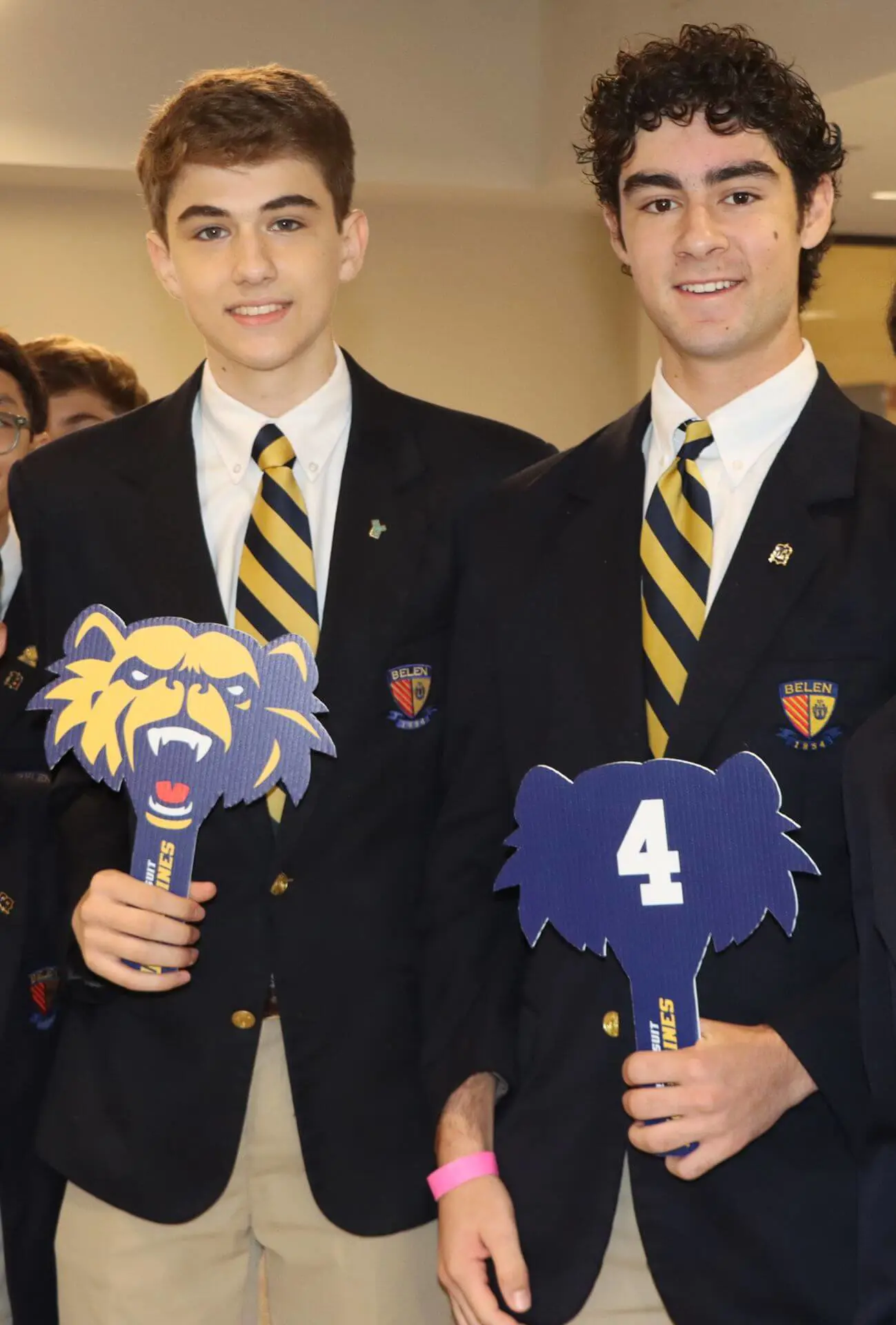 Group of Belen Jesuit student tour leaders, each holding up a Wolverine-shaped number paddle to indicate their respective group for prospective students.