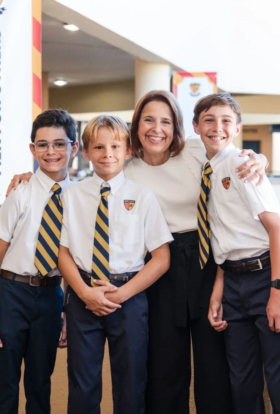 Assistant Principal Patricia Bustamant and three Belen Jesuit Middle School students in uniform stand outdoors.