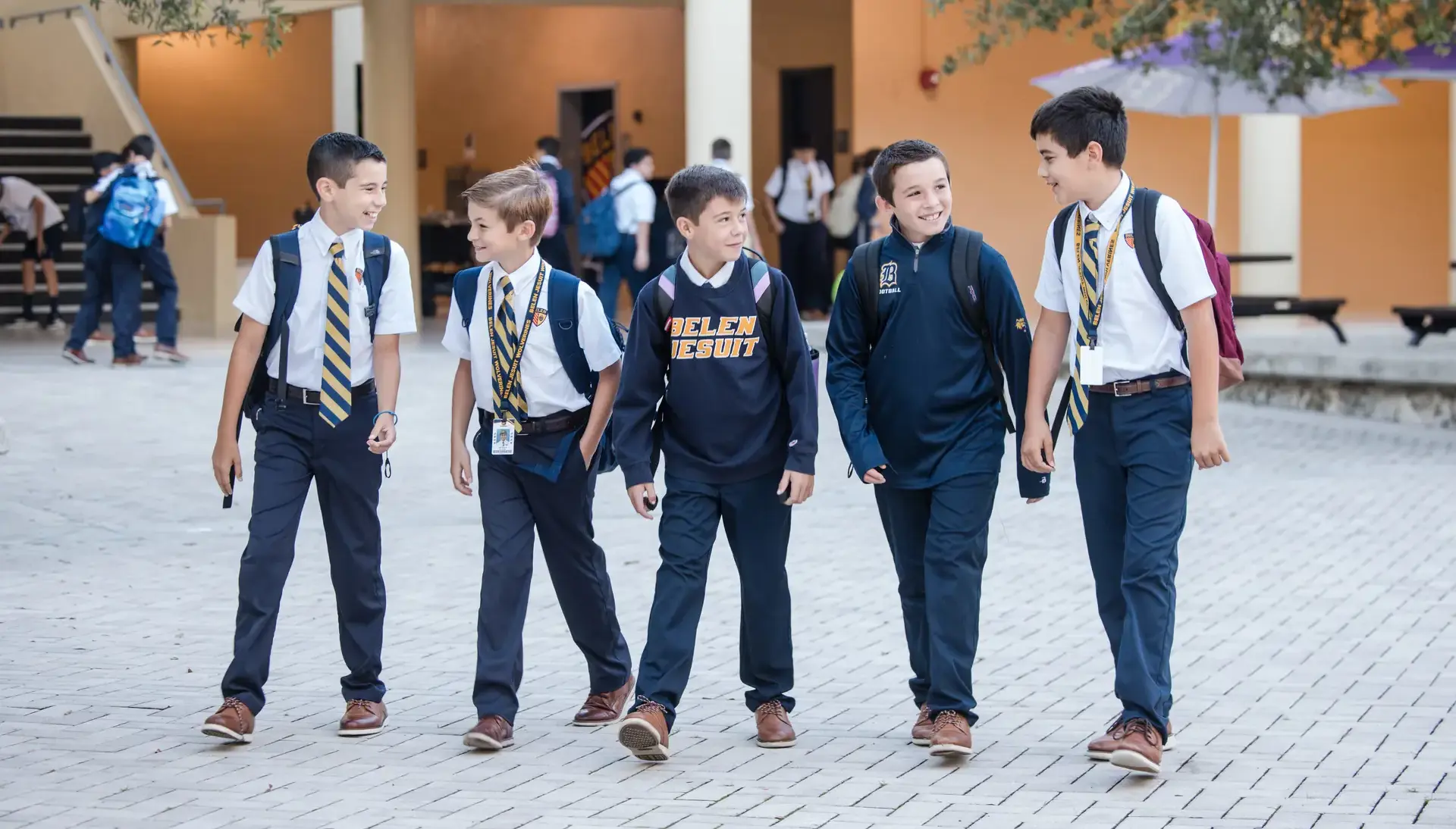 Belen Jesuit students walking across the Garrido Family Plaza before the first bell on a sunny day.