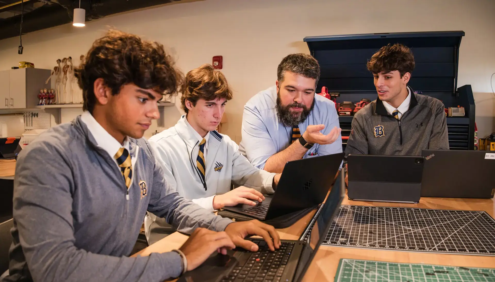 Belen Jesuit teacher Peter Perez is pictured leading his Honors Design & Innovation class. High school students are seated at tables in the Roberto C. Goizueta Innovation Center, engaged in a lesson a