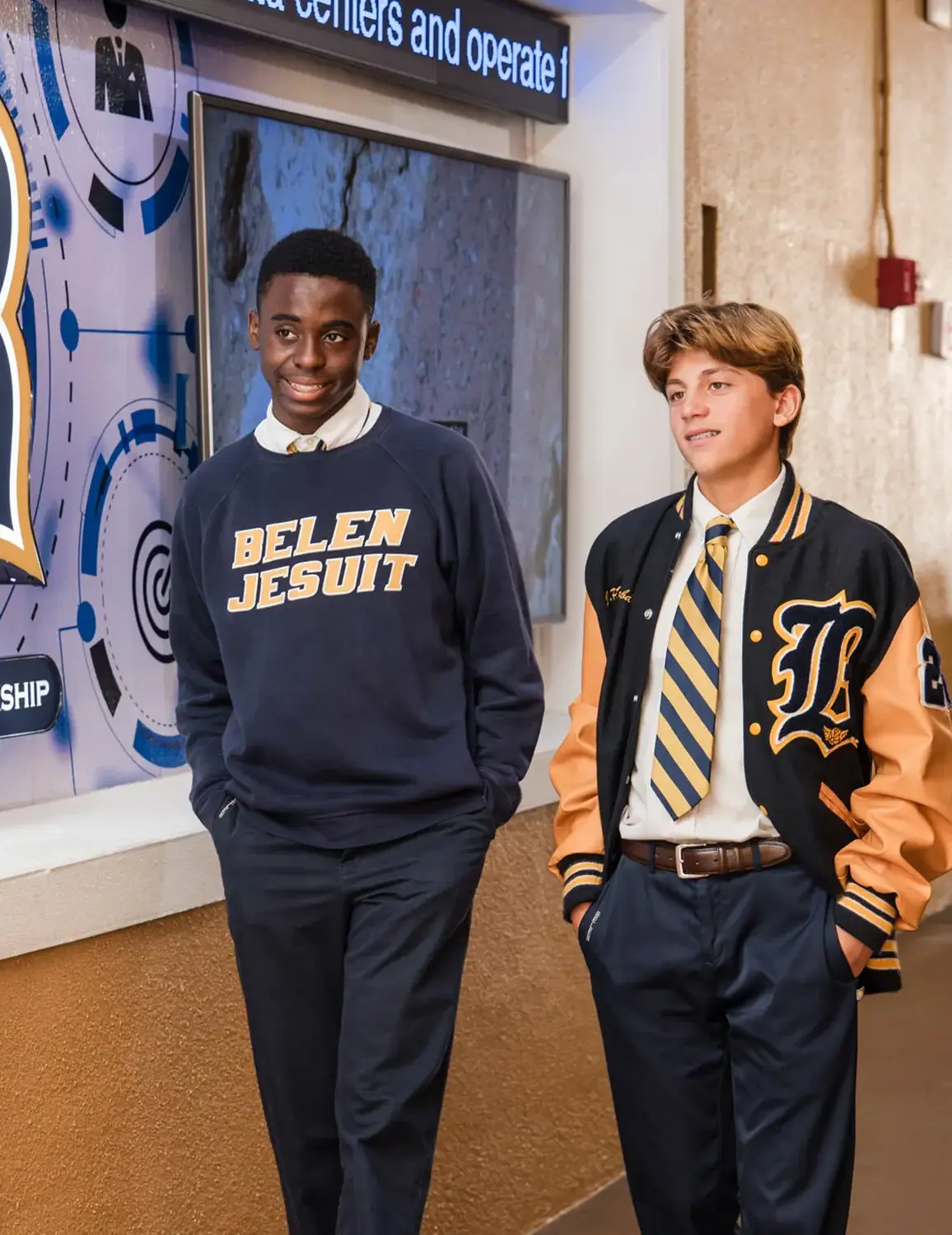 Belen Jesuit high school students walking through hallway together past school logo.