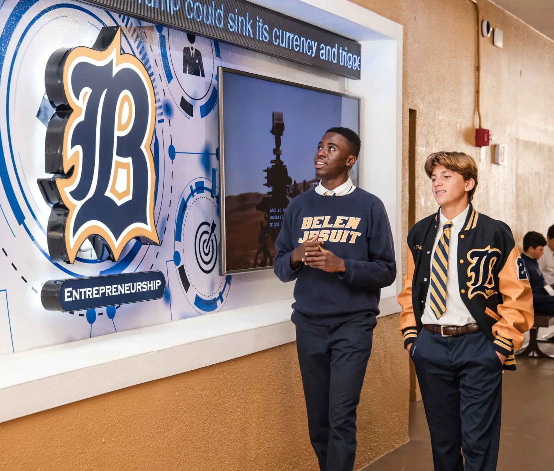 Belen Jesuit high school students walking through hallway together past school logo.