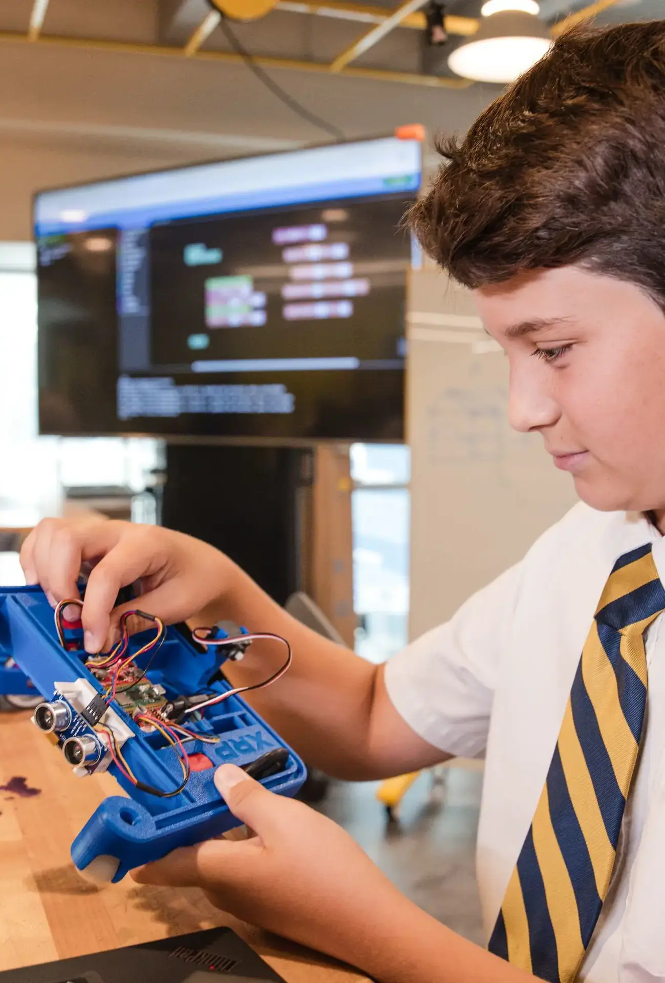 Middle school student assembling a robot or working with components during his robotics class, located in the Roberto C. Goizueta Innovation Center.