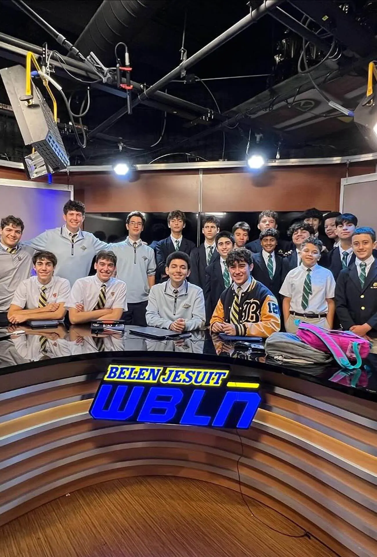 A group of St. Kevin Catholic School students on a tour of the WBLN studio. They are pictured posing on the news desk set alongside members of the Belen Jesuit newscast and crew.