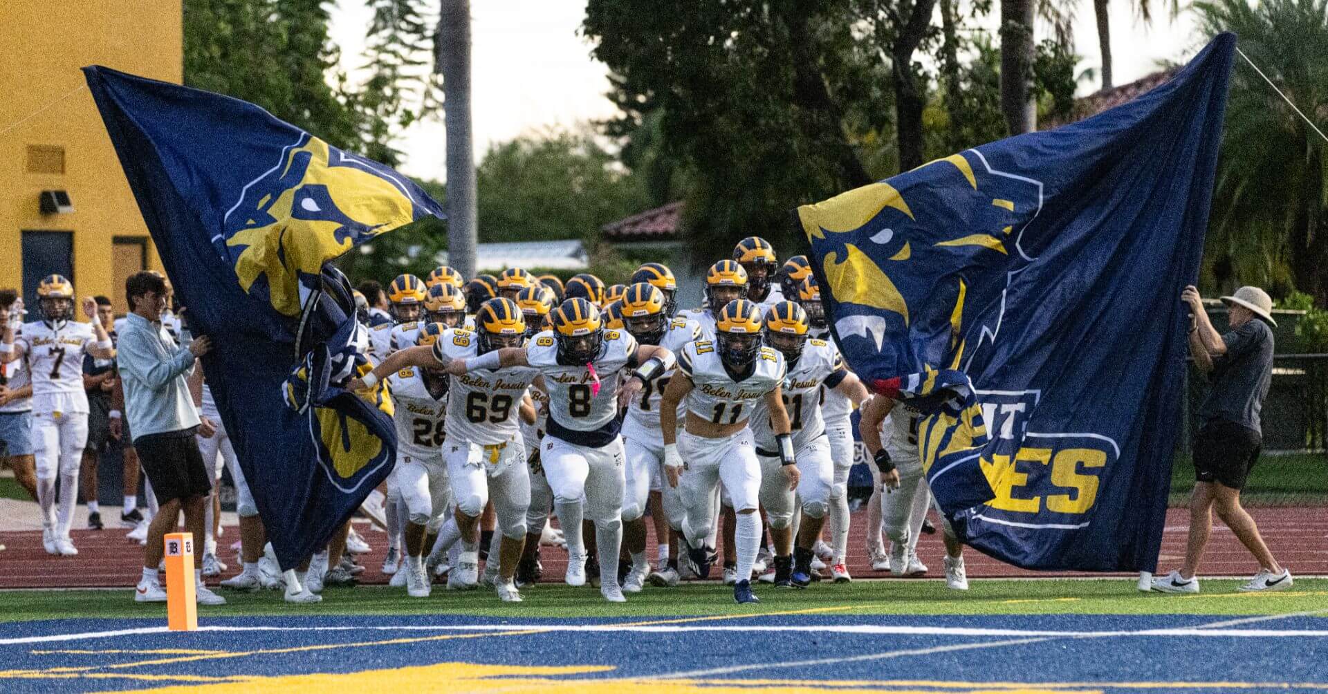 Varsity Football Team running onto sports field.