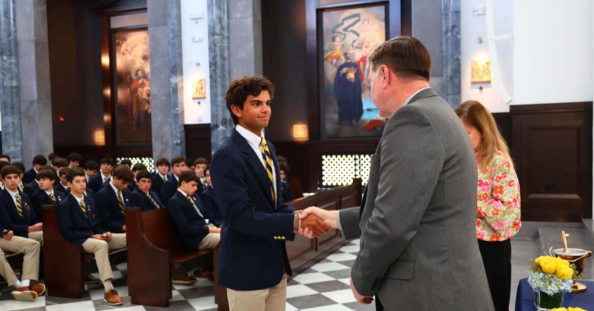 Belen Jesuit student shaking hands with the principal at the NHS Induction Ceremony