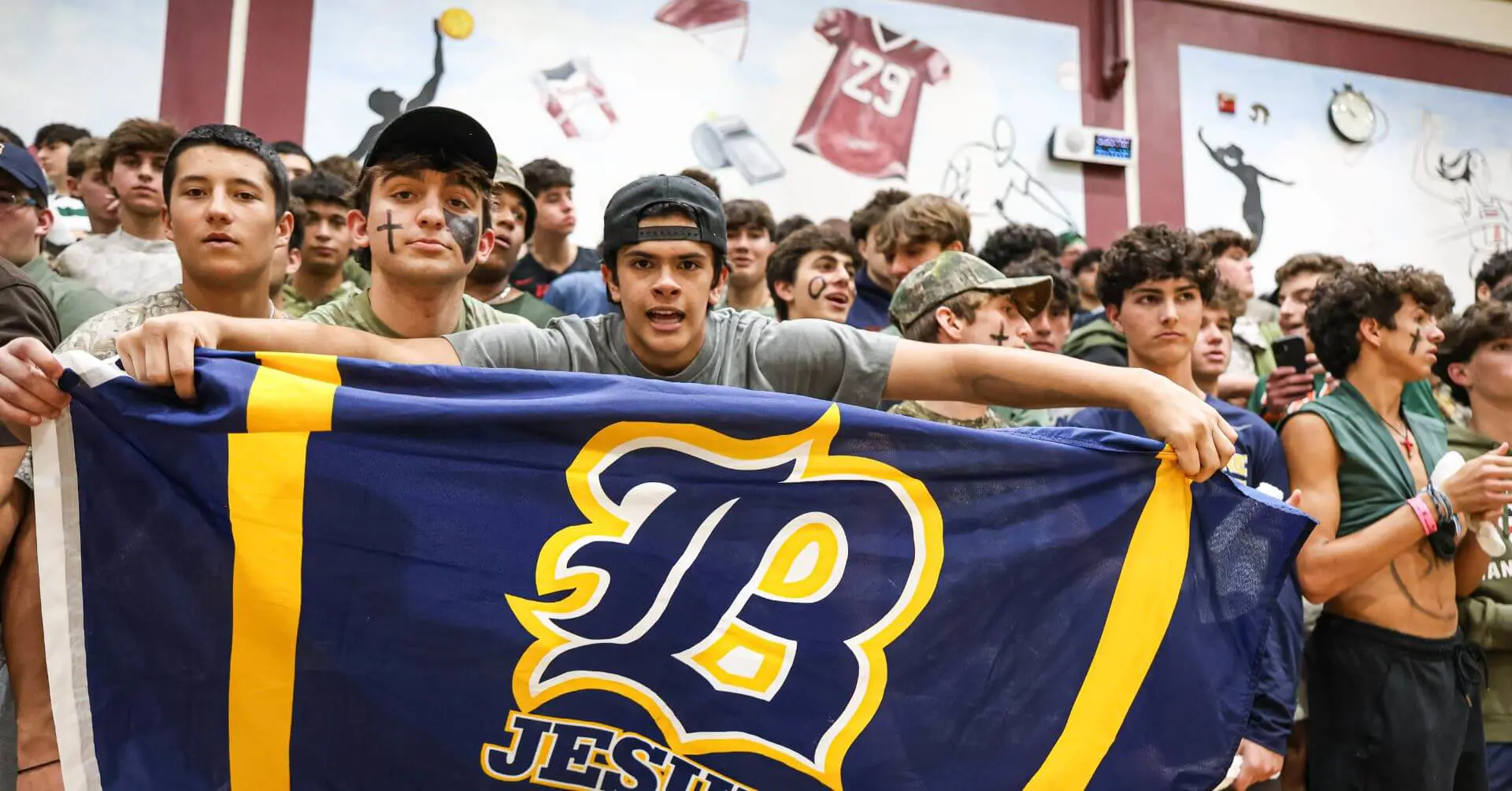 Belen students holding up a Belen Jesuit flag at a sports game.