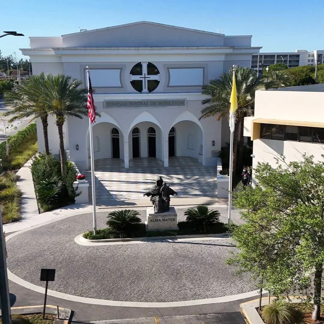 Bird's-eye view of the main entrance and courtyard of the Our Lady of Belen Chapel at Belen Jesuit Preparatory School. The photo highlights the chapel's architectural details and the surrounding paved area.