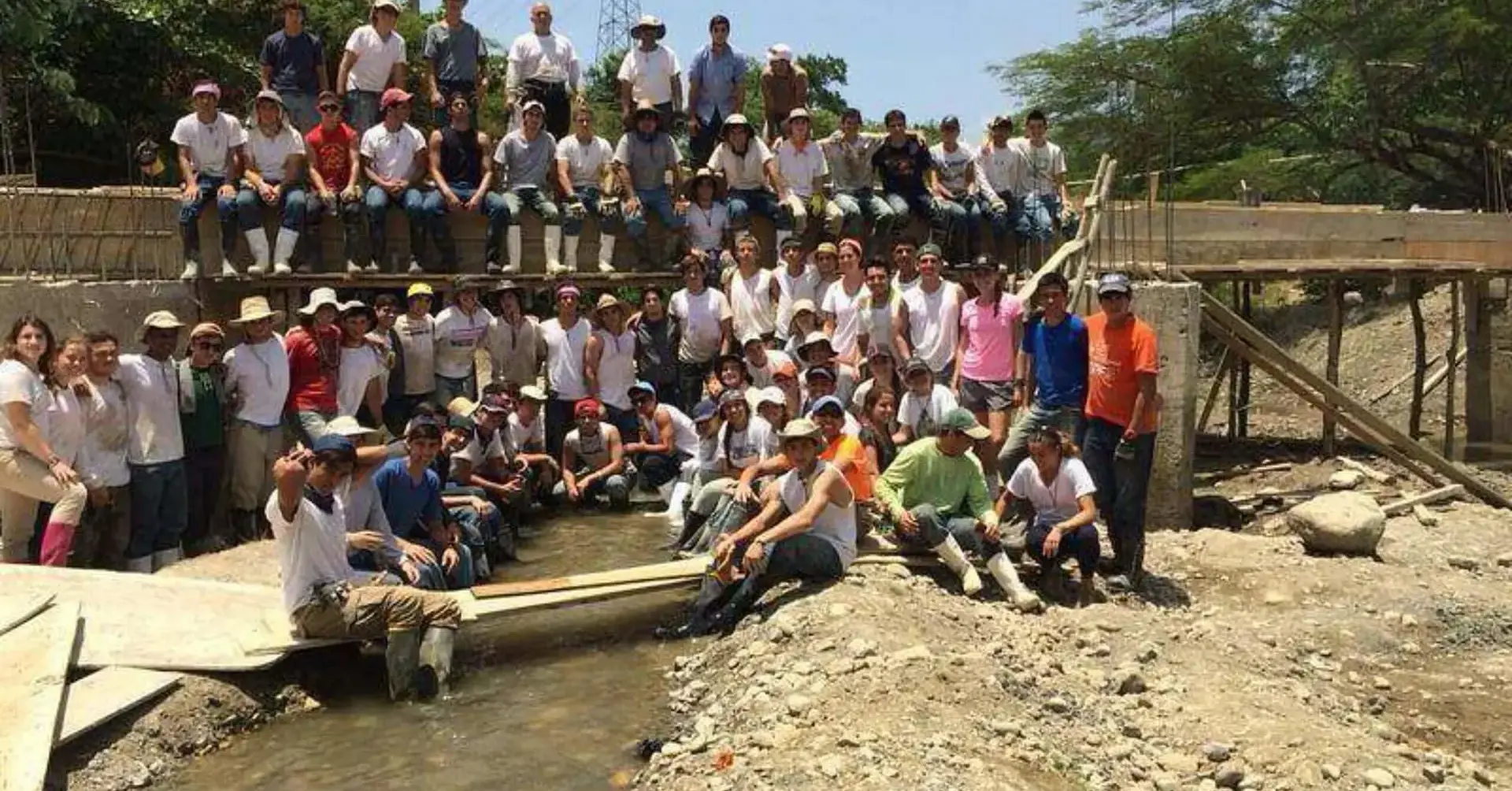 Students participating in the 2014 Belen Youth Mission pose for a photograph on a construction site over a river.