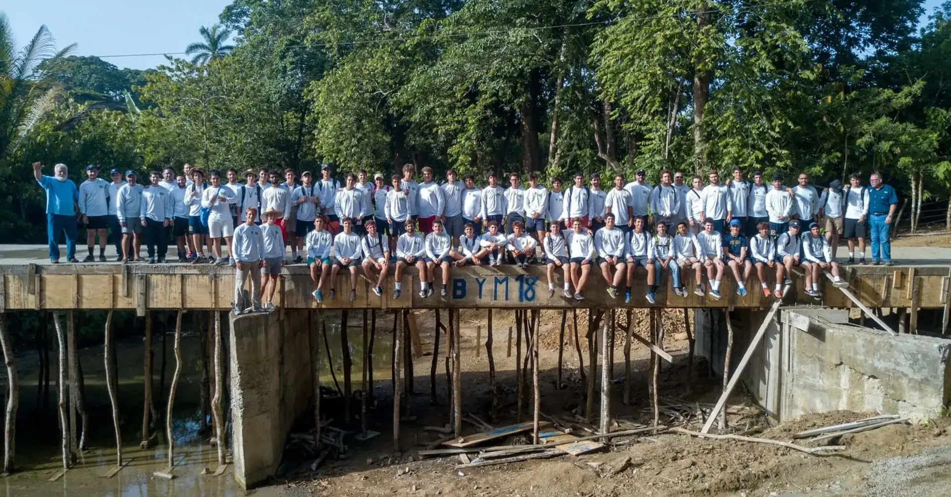 Students participating in the 2018 Belen Youth Mission sitting on a wooden bridge.