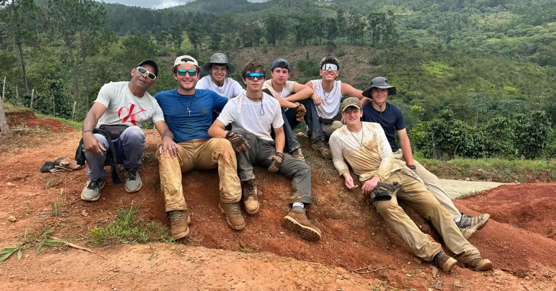 Students participating in the 2024 Belen Youth Mission sitting together on a hillside.