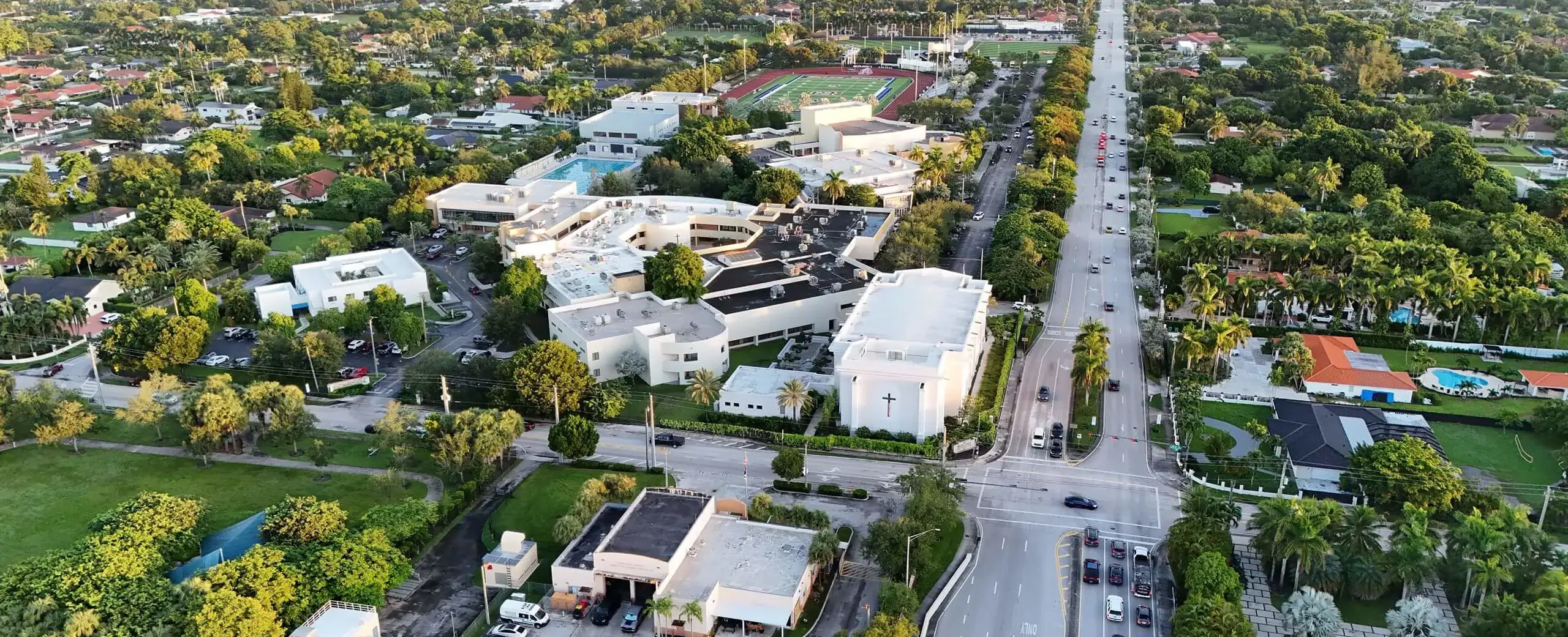 The photo clearly shows the Our Lady of Belen Chapel, the main academic buildings, athletic fields, and the surrounding landscaping.