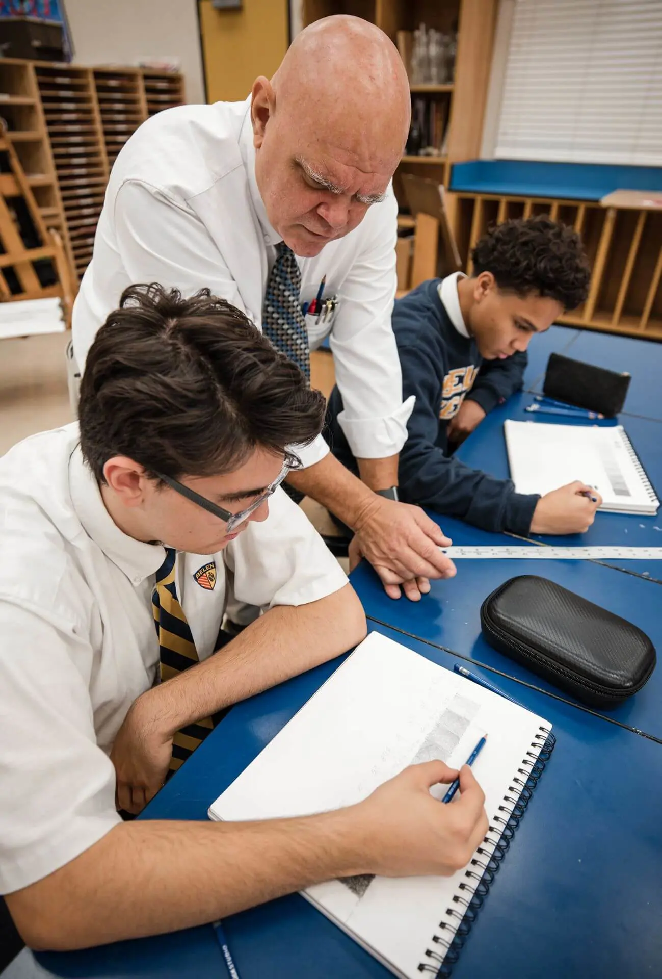 Belen Jesuit art teacher Ignacio Font assists high school students working on a project.